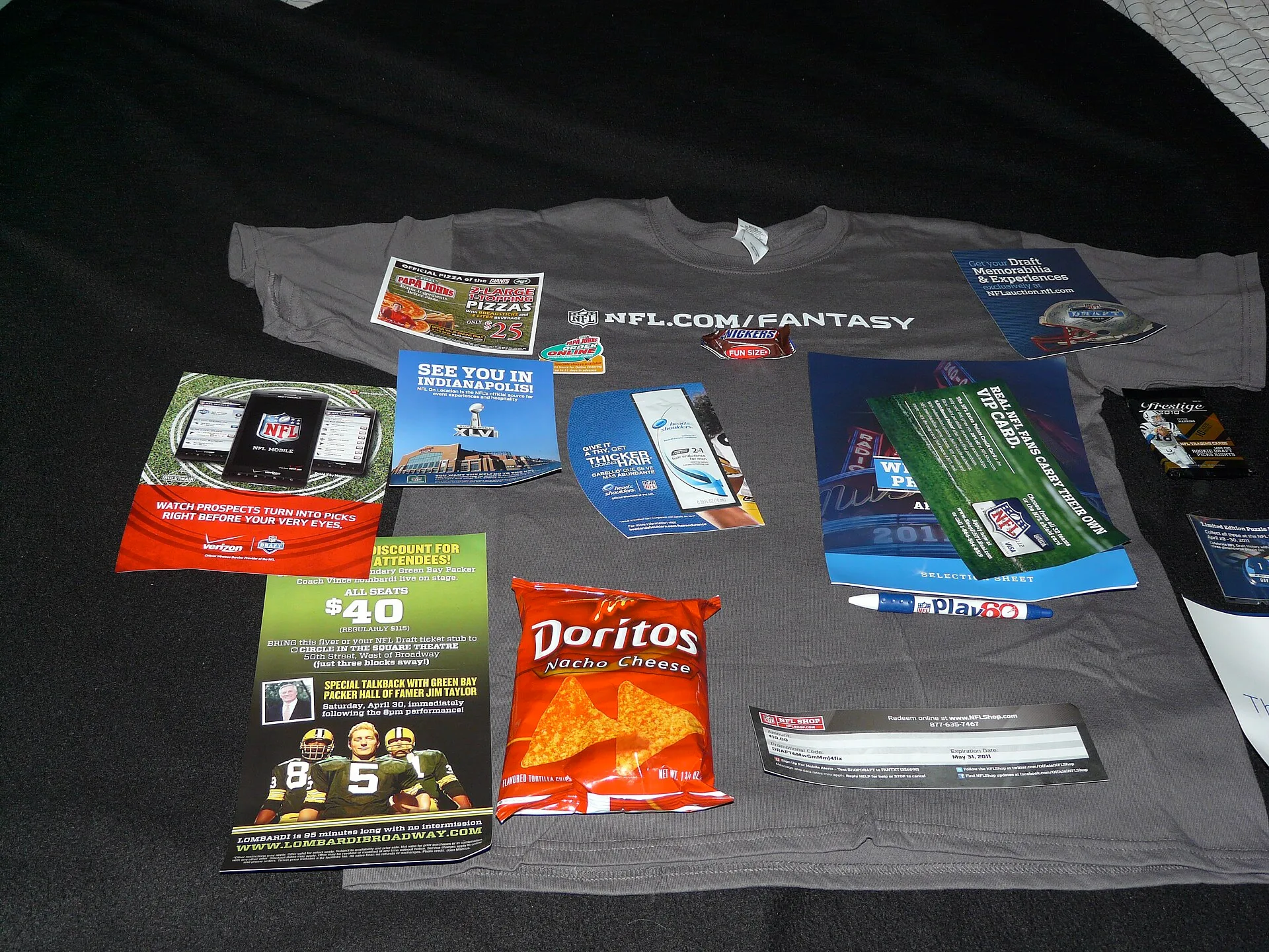 From a tee-shirt to a Snickers bar, a Play 60 pen, a bag of Doritos, assorted coupons for play tickets ("Lombardi"), Verizon phones, Papa John's Pizza (and a magnet!), football cards, draft guide.