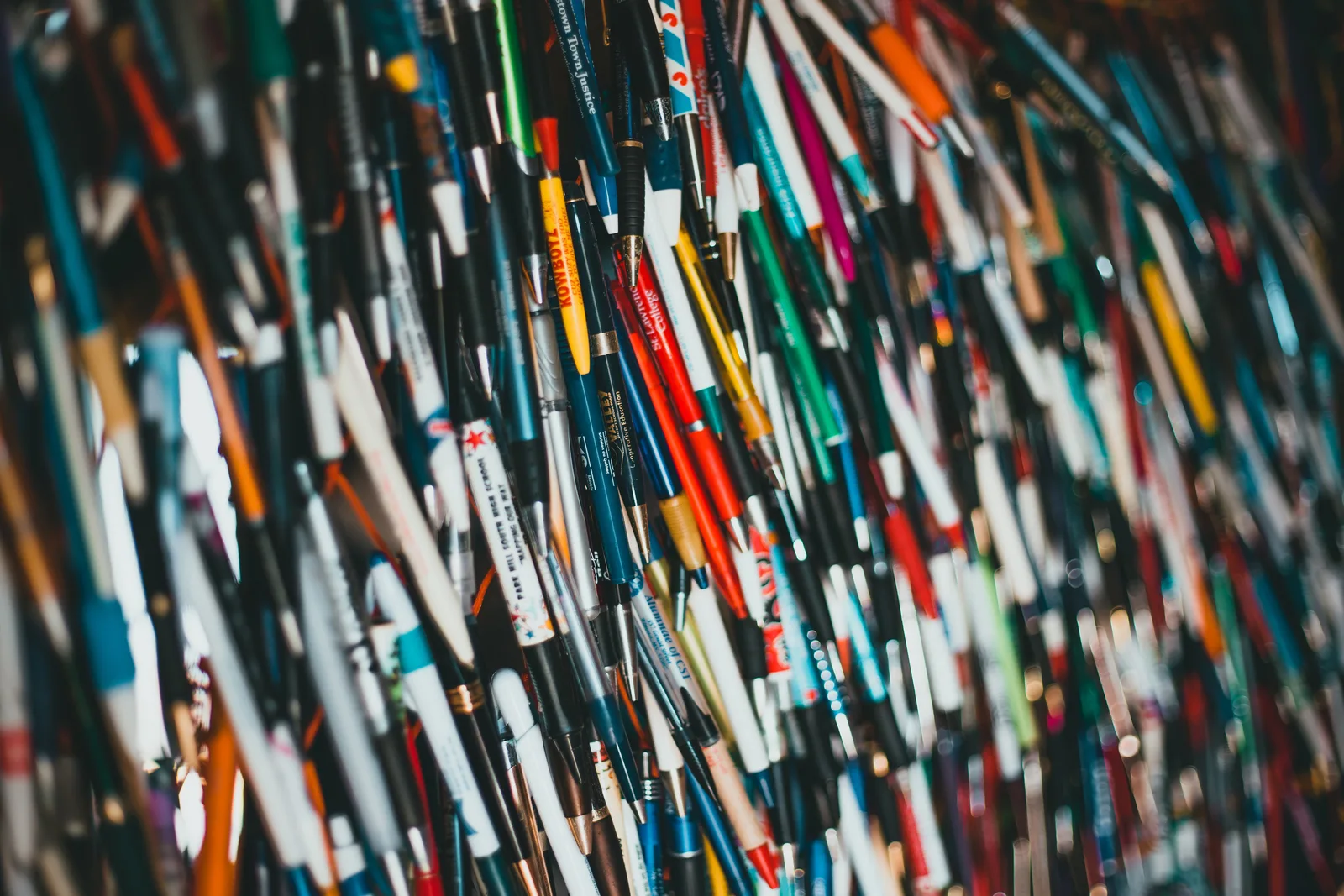 Close-up of a vibrant and diverse collection of pens hanging together, showcasing various brands and colors.