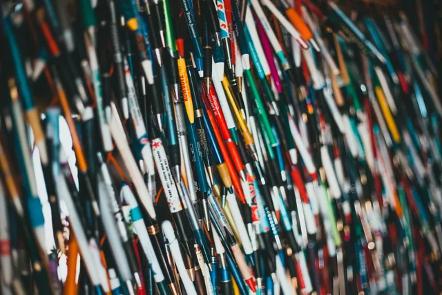 Close-up of a vibrant and diverse collection of pens hanging together, showcasing various brands and colors. How the CAP Code applies to promotional products